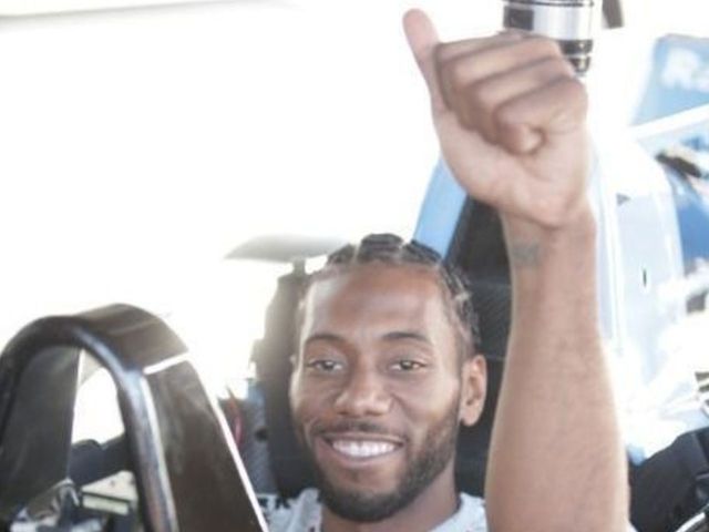 Smiley Kawhi Leonard drives with Mario Andretti at IndyCar finale