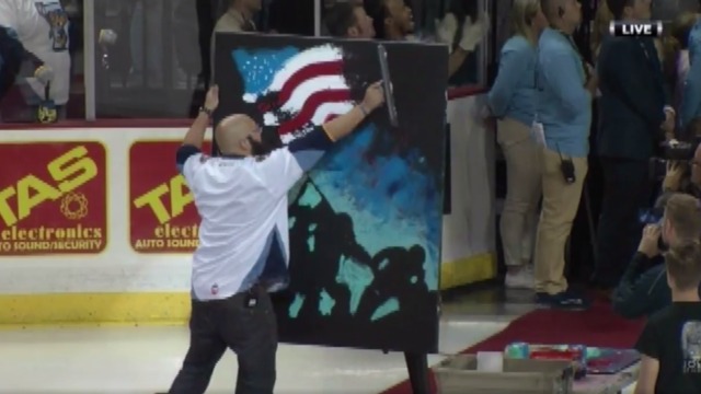 Man paints canvas while singing national anthem at ECHL game