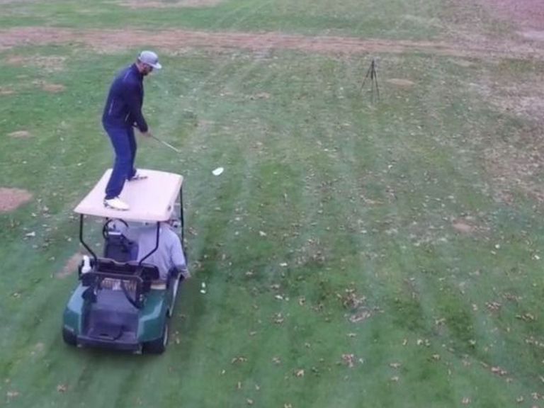 Golfer hits trick shot atop moving golf cart