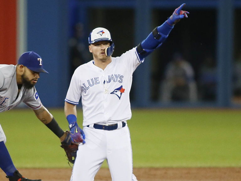 Josh Donaldson #20 of the Toronto Blue Jays puts on his helmet as he walks  back to third during a game …