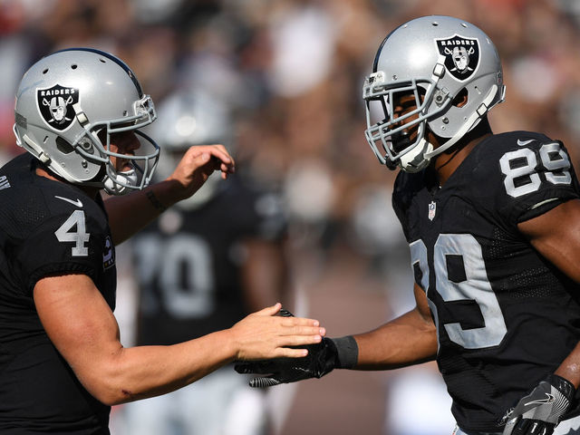 OAKLAND, CA - OCTOBER 09: Derek Carr #4 of the Oakland Raiders celebrates with Amari Cooper #89 after a scoring on a two-point conversion against the San Diego Chargers during their NFL game at Oakland-Alameda County Coliseum on October 9, 2016 in Oakland, California.