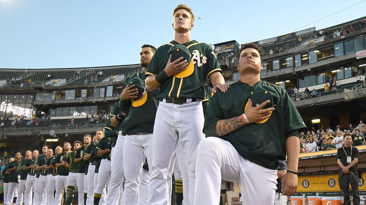 OAKLAND, CA - SEPTEMBER 26: Bruce Maxwell #13 of the Oakland Athletics kneels in protest next to teammate Mark Canha #20 duing the singing of the National Anthem prior to the start of the game against the Seattle Mariners at Oakland Alameda Coliseum on September 26, 2017 in Oakland, California.