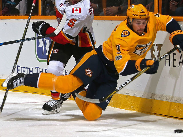 NASHVILLE, TN - OCTOBER 24: Mark Giordano #5 of the Calgary Flames trips Filip Forsberg #9 of the Nashville Predators during the first period at Bridgestone Arena on October 24, 2017 in Nashville, Tennessee.