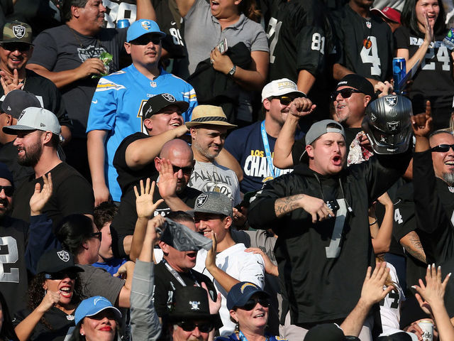 CARSON, CA - DECEMBER 31: A Los Angeles Chargers fan is seen surrounded by Oakland Raiders fans during the first half of the game at StubHub Center on December 31, 2017 in Carson, California.