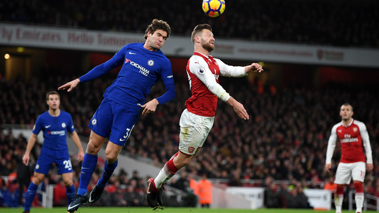LONDON, ENGLAND - JANUARY 03: Marcos Alonso of Chelsea and Shkodran Mustafi of Arsenal battle for possession in the air during the Premier League match between Arsenal and Chelsea at Emirates Stadium on January 3, 2018 in London, England.