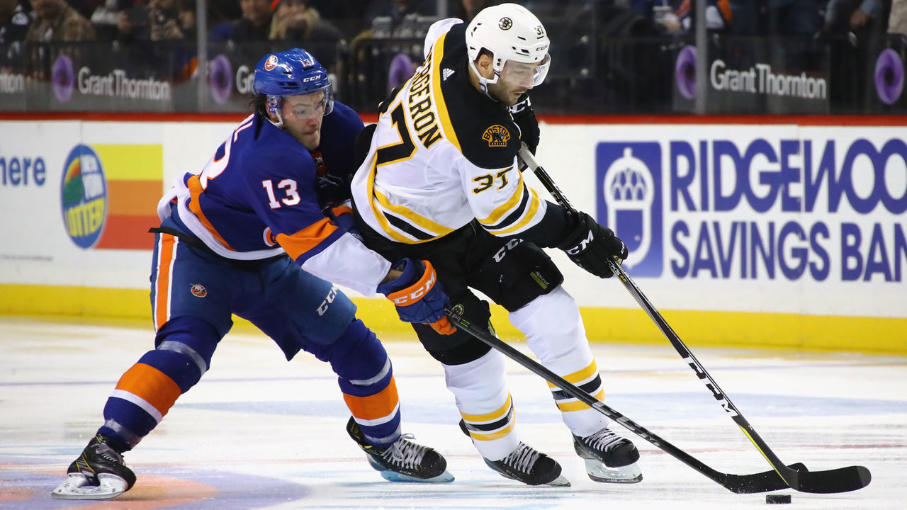 NEW YORK, NY - JANUARY 02: Patrice Bergeron #37 of the Boston Bruins carries the puck as Mathew Barzal #13 of the New York Islanders backchecks during the first period at the Barclays Center on January 2, 2018 in the Brooklyn borough of New York City.