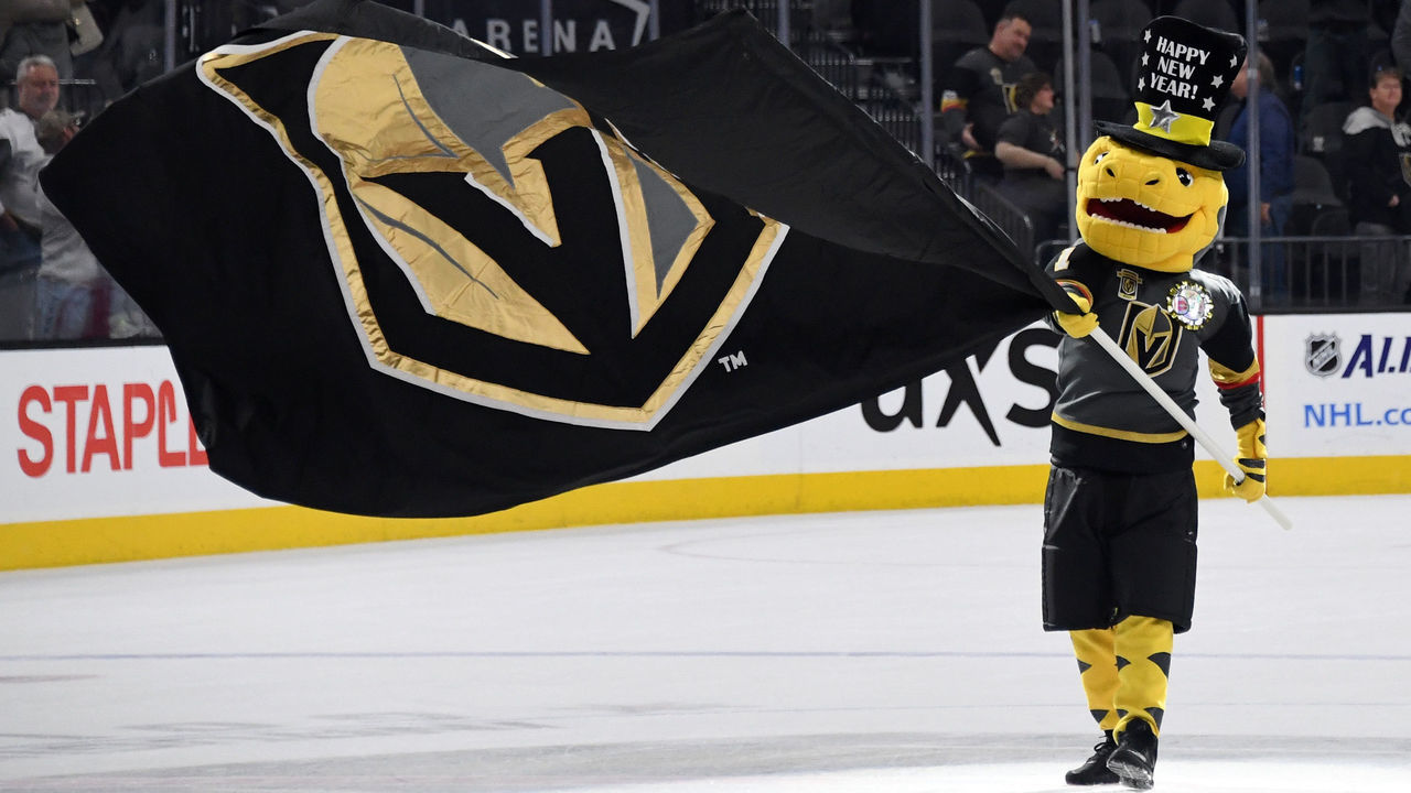 LAS VEGAS, NV - DECEMBER 31: The Vegas Golden Knights mascot Chance the Golden Gila Monster waves a Knights flag at center ice after the team defeated the Toronto Maple Leafs 6-3 at T-Mobile Arena on December 31, 2017 in Las Vegas, Nevada.