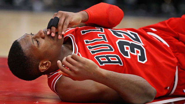 CHICAGO, IL - JANUARY 17: Kris Dunn #32 of the Chicago Bulls lays on the floor after suffering a mouth injury following a dunk against the Golden State Warriors at the United Center on January 17, 2018 in Chicago, Illinois. The Warriors defeated the Bulls 119-112.