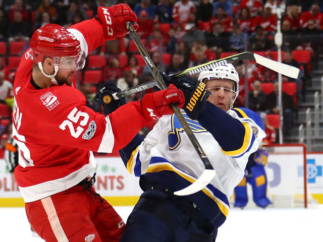 DETROIT, MI - DECEMBER 09: Mike Green #25 of the Detroit Red Wings lays a first period hit on Carl Gunnarsson #4 of the St. Louis Blues at Little Caesars Arena on December 9, 2017 in Detroit, Michigan.
