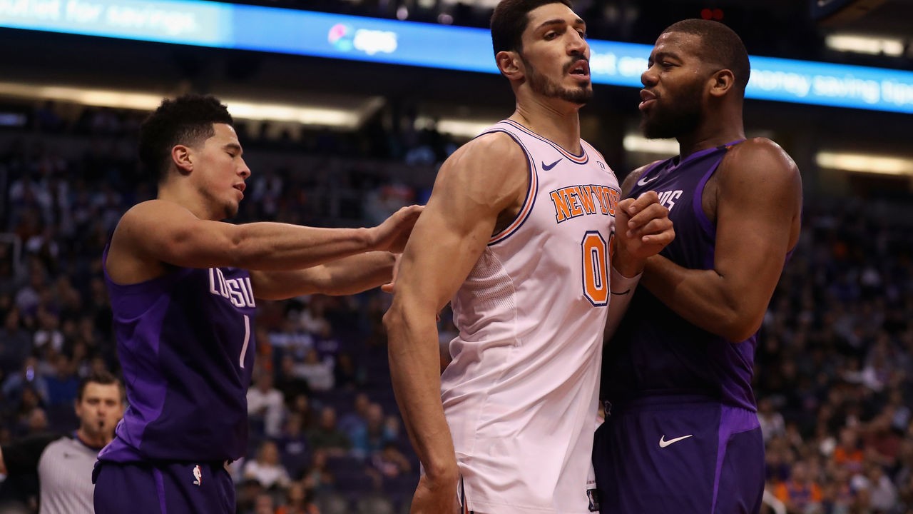 PHOENIX, AZ - JANUARY 26: Devin Booker #1 of the Phoenix Suns pushes Enes Kanter #00 of the New York Knicks into Greg Monroe #14 during the second half of the NBA game at Talking Stick Resort Arena on January 26, 2018 in Phoenix, Arizona. Both Booker and Kanter received technical fouls.