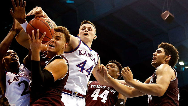 LAWRENCE, KS - JANUARY 27: DJ Hogg #1 of the Texas A&M Aggies tries to control the ball as Lagerald Vick #2 and Mitch Lightfoot #44 of the Kansas Jayhawks defend during the game at Allen Fieldhouse on January 27, 2018 in Lawrence, Kansas.