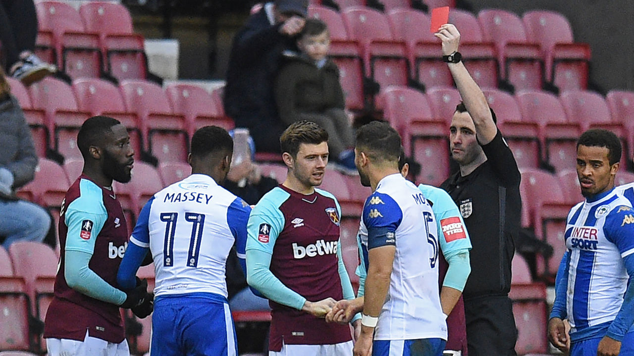 West Ham United's French defender Arthur Masuaku (L) is shown a red card by referee Chris Kavanagh during the English FA Cup fourth round football match between Wigan Athletic and West Ham United at the DW Stadium in Wigan, northwest England, on January 27, 2018. / AFP PHOTO / Oli SCARFF /