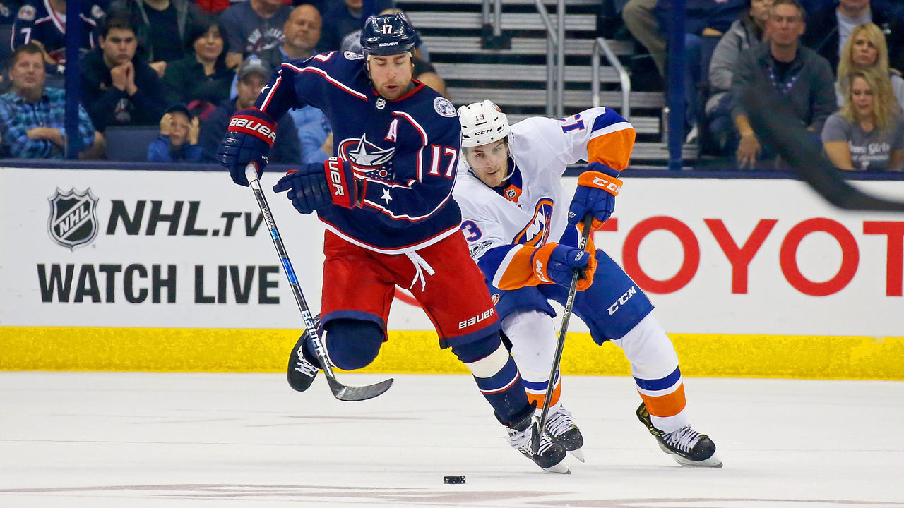 COLUMBUS, OH - OCTOBER 6: Brandon Dubinsky #17 of the Columbus Blue Jackets skates the puck up the ice and away from Mathew Barzal #13 of the New York Islanders during the second period on October 6, 2017 at Nationwide Arena in Columbus, Ohio.