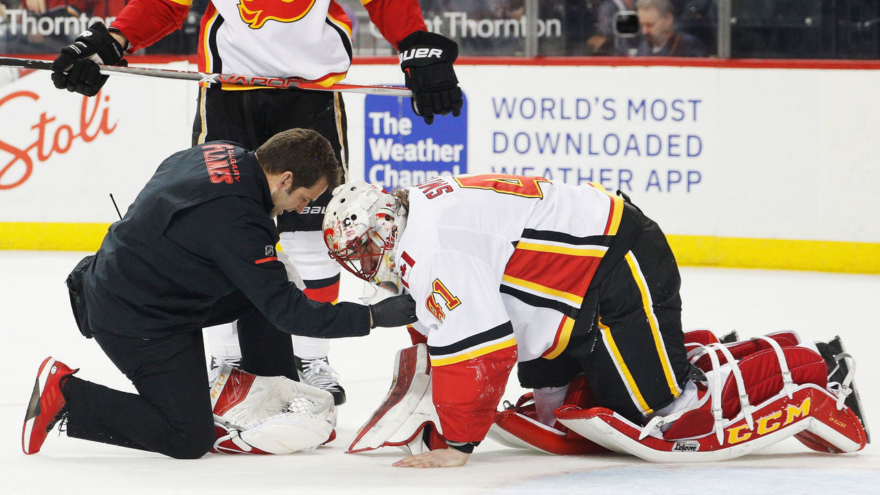 NEW YORK, NY - FEBRUARY 11: A trainer tends to Mike Smith #41 of the Calgary Flames during the final moments of a 3-2 win against the New York Islanders at Barclays Center on February 11, 2018 in the Brooklyn borough of New York City.