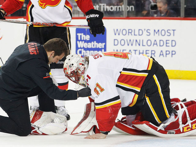 NEW YORK, NY - FEBRUARY 11: A trainer tends to Mike Smith #41 of the Calgary Flames during the final moments of a 3-2 win against the New York Islanders at Barclays Center on February 11, 2018 in the Brooklyn borough of New York City.