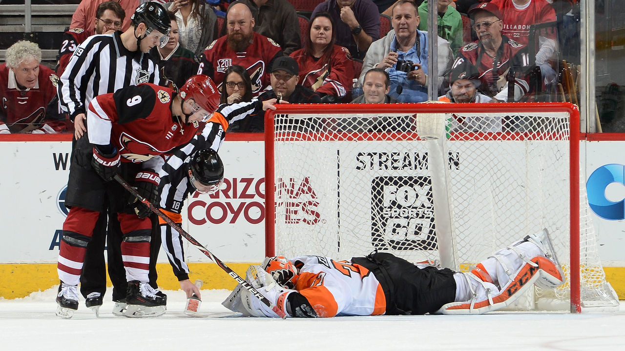 GLENDALE, AZ - FEBRUARY 10: Clayton Keller #9 of the Arizona Coyotes, referee Tom Chmielewski #18 and linesman Kiel Murchison #79 check to see if goaltender Brian Elliott #37 of the Philadelphia Flyers is injured during a shootout at Gila River Arena on February 10, 2018 in Glendale, Arizona. Elliott was helped from the ice and was replaced by Michal Neuvirth. Flyers won 4-3.