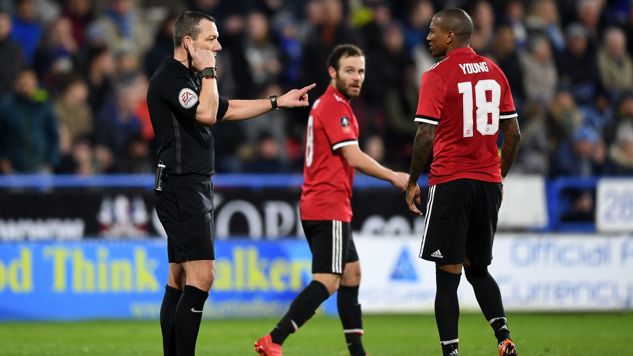 HUDDERSFIELD, ENGLAND - FEBRUARY 17: Referee Kevin Friend consults with the Video Assistant Referee as Manchester United players await a decision over a Juan Mata of Manchester United goal during the The Emirates FA Cup Fifth Round between Huddersfield Town v Manchester United on February 17, 2018 in Huddersfield, United Kingdom.