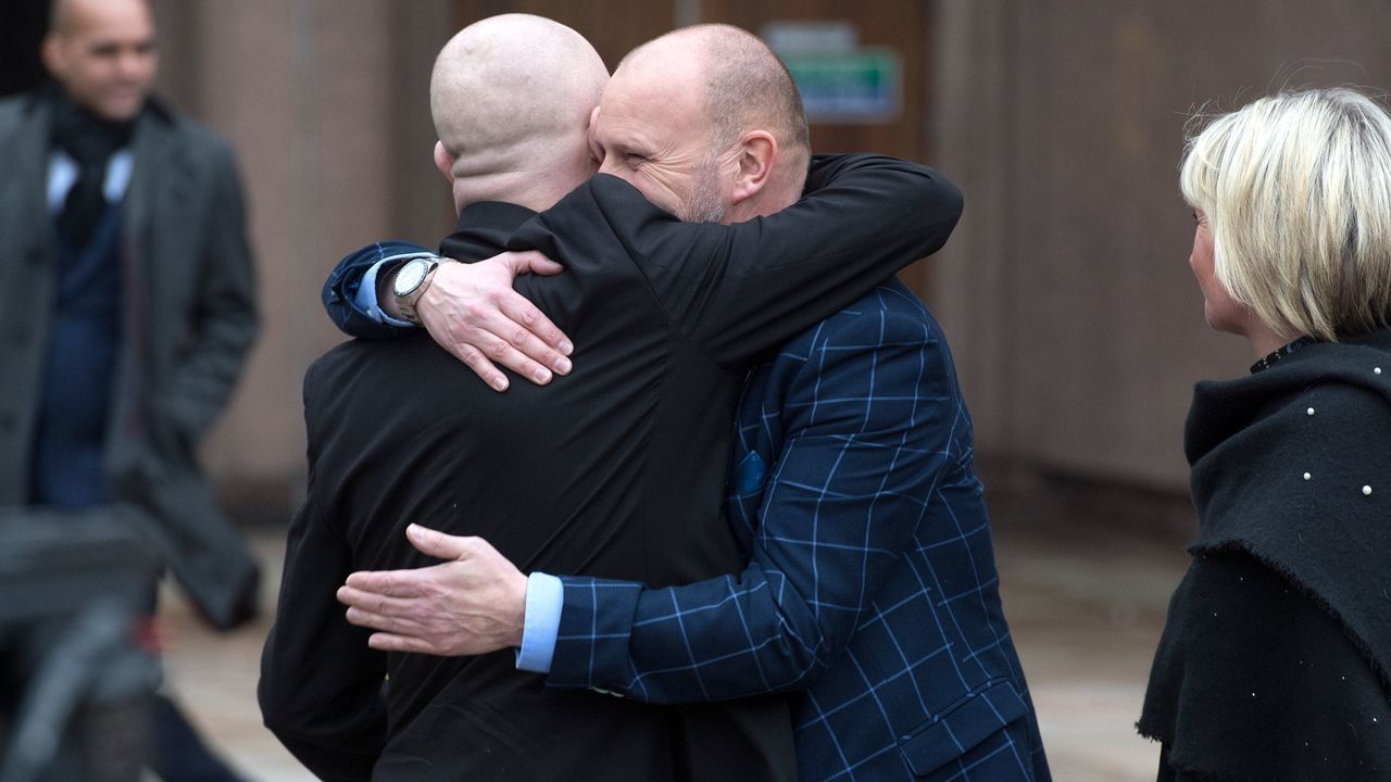 Victims of abuse by former football coach Barry Bennell, Jason Dunsford (L) and Chris Unsworth (2L), embrace outside Liverpool Crown Court on February 19, 2018 as the sentencing hearing for former football coach Barry Bennell who was found guilty of sexual abuse is adjourned for lunch. Disgraced former British youth coach Barry Bennell was on February 15 found guilty of 43 counts of sexual abuse against 11 boys aged between eight and 15 in a case that has rocked English football. / AFP PHOTO / Anthony Devlin