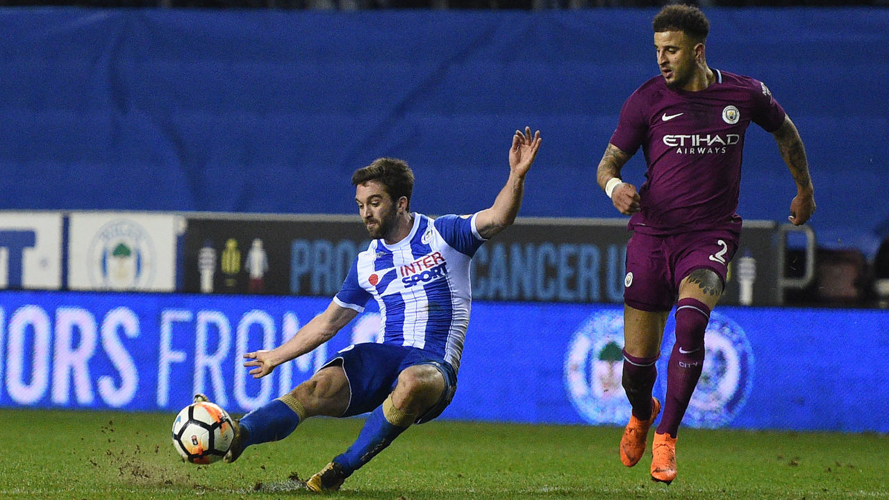 Wigan Athletic's English-born Northern Irish striker Will Grigg (L) scores his team's first goal during the English FA Cup fifth round football match between Wigan Athletic and Manchester City at the DW Stadium in Wigan, northwest England, on February 19, 2018. / AFP PHOTO / Oli SCARFF /