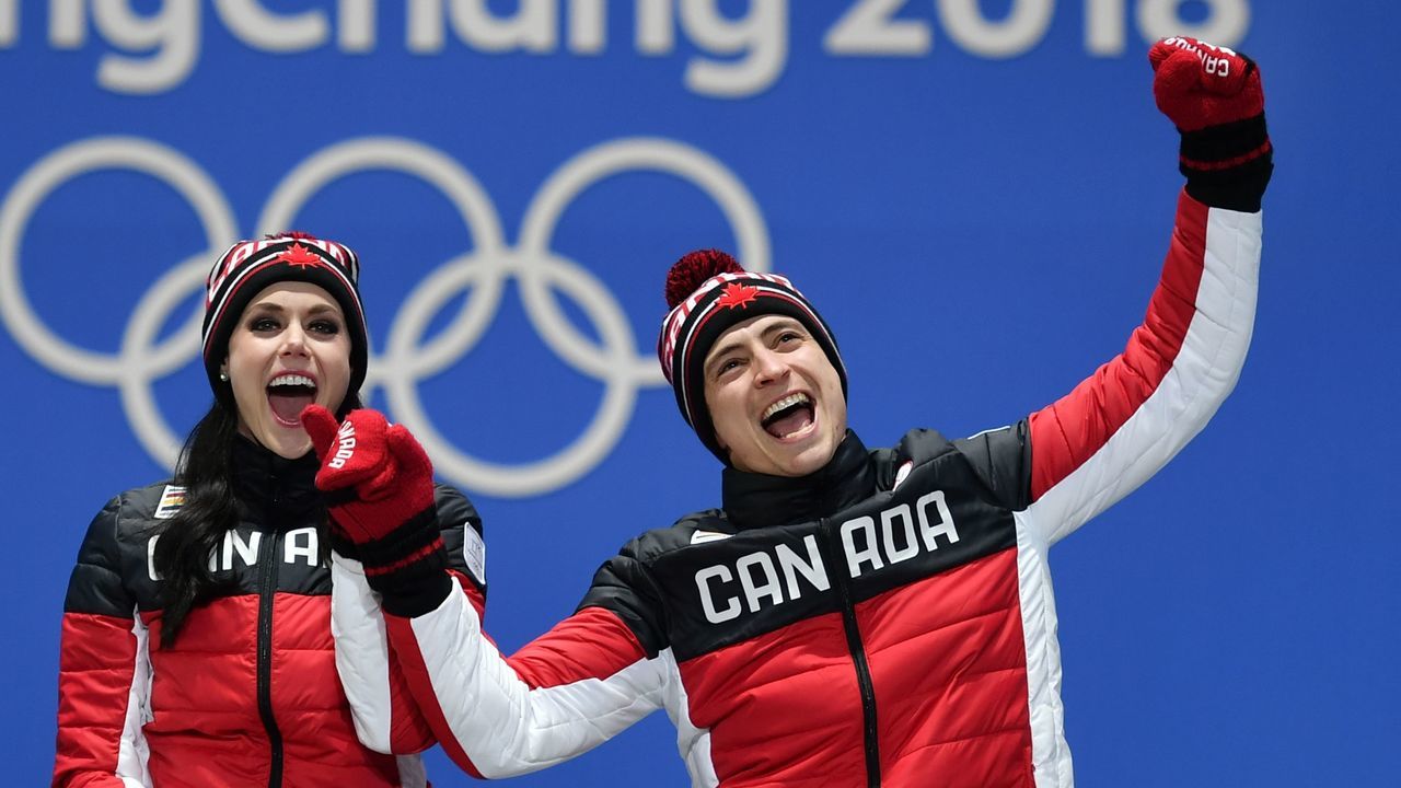 TOPSHOT - Canada's gold medallists Tessa Virtue (L) and Scott Moir celebrate on the podium during the medal ceremony for the figure skating ice dance at the Pyeongchang Medals Plaza during the Pyeongchang 2018 Winter Olympic Games in Pyeongchang on February 20, 2018. / AFP PHOTO / Fabrice COFFRINI