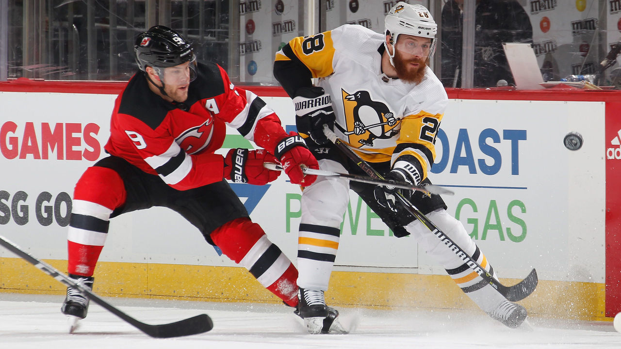 NEWARK, NJ - FEBRUARY 03: Ian Cole #28 of the Pittsburgh Penguins shoots the puck as Taylor Hall #9 of the New Jersey Devils defends in the first period of an NHL hockey game at Prudential Center on February 3, 2018 in Newark, New Jersey.
