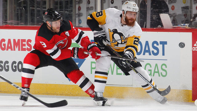 NEWARK, NJ - FEBRUARY 03: Ian Cole #28 of the Pittsburgh Penguins shoots the puck as Taylor Hall #9 of the New Jersey Devils defends in the first period of an NHL hockey game at Prudential Center on February 3, 2018 in Newark, New Jersey.