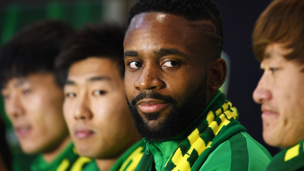 Congolese football player Cedric Bakambu (2nd R) smiles as he is introduced at a press conference by his new team Beijing Guoan in Beijing on March 1, 2018. Chinese Super League club Beijing Guoan officially presented their new striker Congolese international Cedric Bakambu on March 1, completing a drawn-out transfer saga from his former Spanish team Villarreal. / AFP PHOTO / Greg Baker
