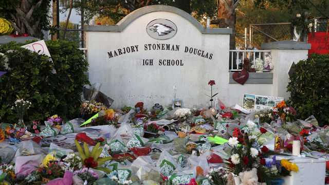 Flowers, candles and mementos sit outside one of the makeshift memorials at Marjory Stoneman Douglas High School in Parkland, Florida on February 27, 2018. Florida's Marjory Stoneman Douglas high school will reopen on February 28, 2018 two weeks after 17 people were killed in a shooting by former student, Nikolas Cruz, leaving 17 people dead and 15 injured on February 14, 2018. / AFP PHOTO / RHONA WISE