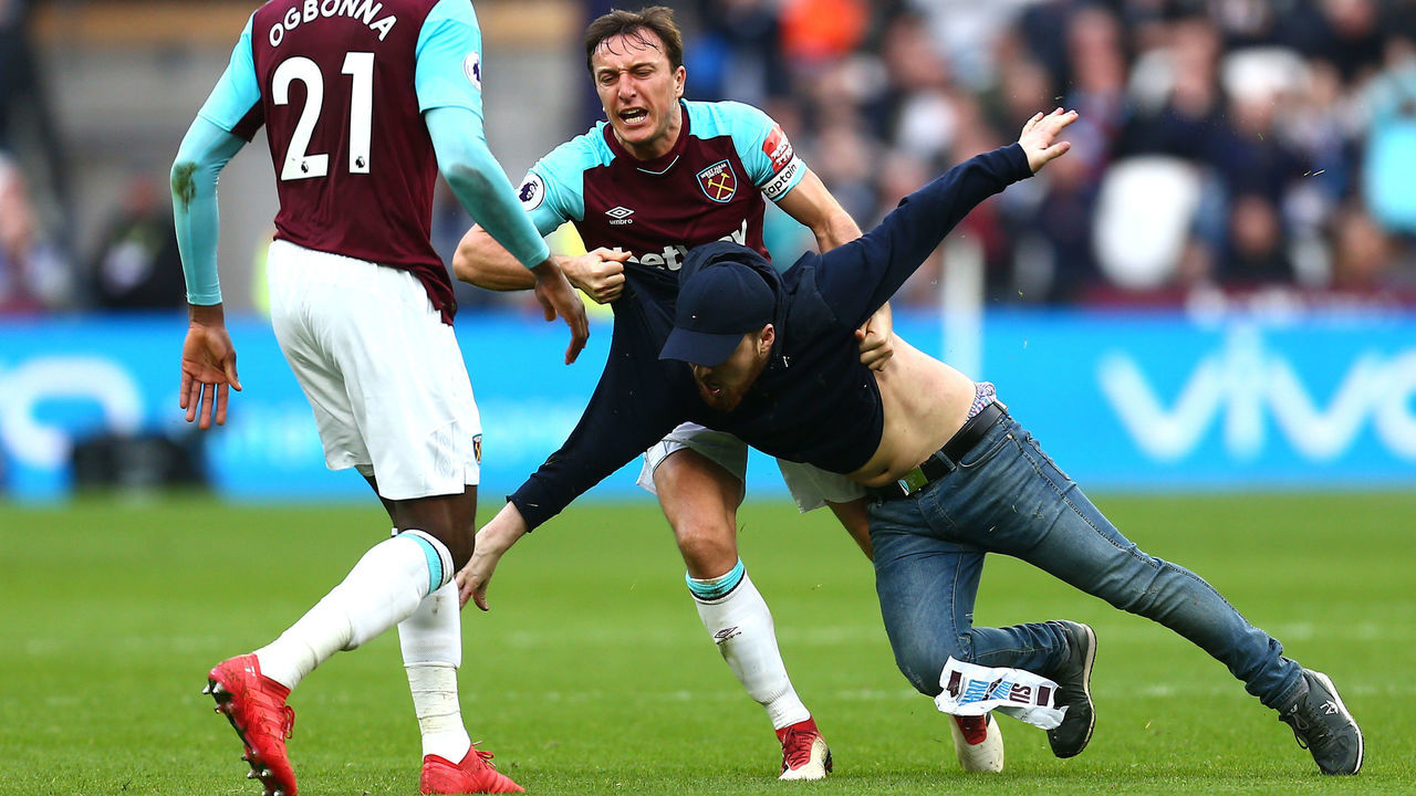LONDON, ENGLAND - MARCH 10: Mark Noble of West Ham United clashes with a pitch invader during the Premier League match between West Ham United and Burnley at London Stadium on March 10, 2018 in London, England.