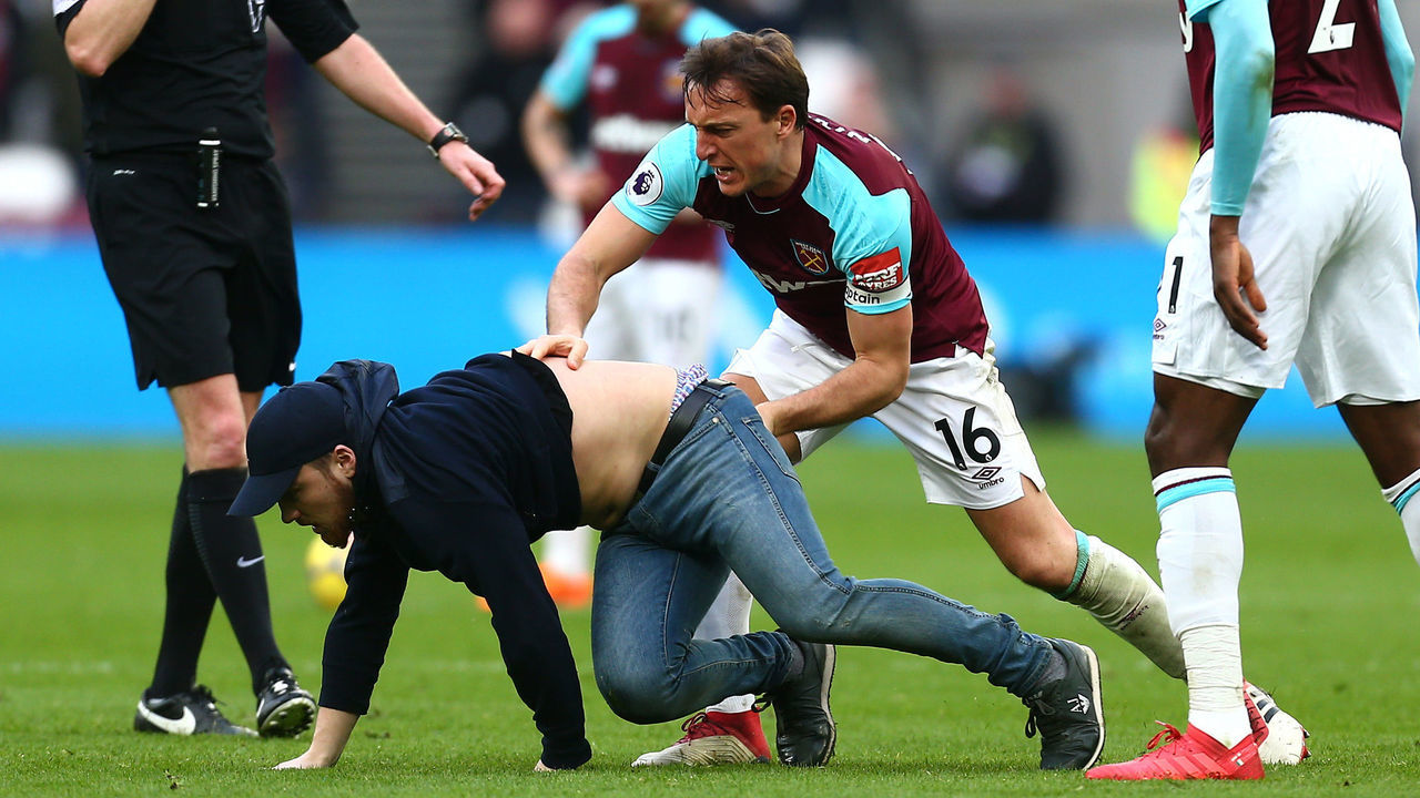 LONDON, ENGLAND - MARCH 10: Mark Noble of West Ham United clashes with a pitch invader during the Premier League match between West Ham United and Burnley at London Stadium on March 10, 2018 in London, England.
