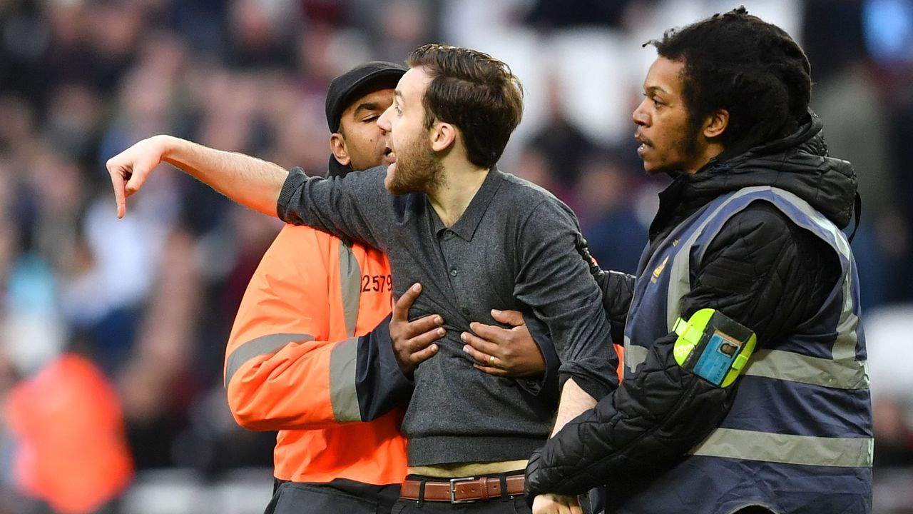 A pitch invader is handled by security during the English Premier League football match between West Ham United and Burnley at The London Stadium, in east London on March 10, 2018. / AFP PHOTO / Ben STANSALL /