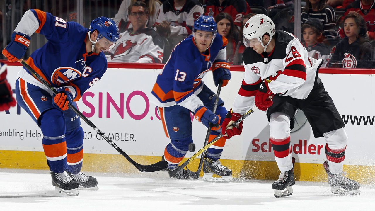 NEWARK, NJ - FEBRUARY 24: Damon Severson #28 of the New Jersey Devils battles for the puck with John Tavares #91 of the Islanders and Mathew Barzal #13 of the New York Islanders during the third period at the Prudential Center on February 24, 2018 in Newark, New Jersey. The Devils won 2-1.