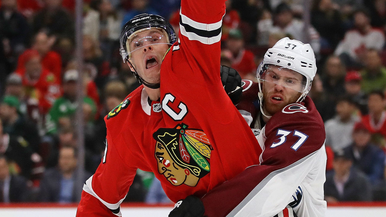 CHICAGO, IL - MARCH 20: Jonathan Toews #19 of the Chicago Blackhawks ctaches an airborne puck wrapped up by J.T. Compher #37 of the Colorado Avalanche at the United Center on March 20, 2018 in Chicago, Illinois.