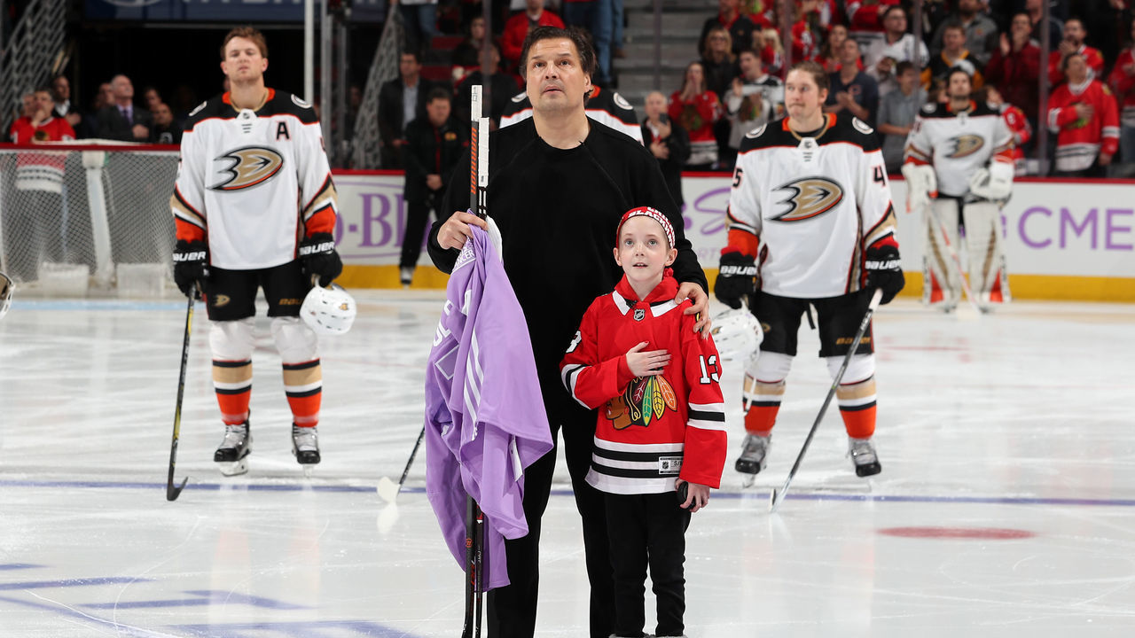CHICAGO, IL - NOVEMBER 27: Former Chicago Blackhawk Eddie Olczyk and 9-year-old cancer patient Lauren Graver stand for the national anthem during 'Hockey Fights Cancer' night prior to the game between the Chicago Blackhawks and the Anaheim Ducks at the United Center on November 27, 2017 in Chicago, Illinois.