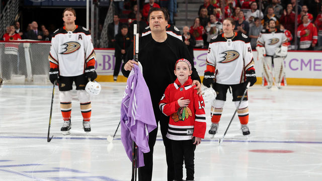 CHICAGO, IL - NOVEMBER 27: Former Chicago Blackhawk Eddie Olczyk and 9-year-old cancer patient Lauren Graver stand for the national anthem during 'Hockey Fights Cancer' night prior to the game between the Chicago Blackhawks and the Anaheim Ducks at the United Center on November 27, 2017 in Chicago, Illinois.