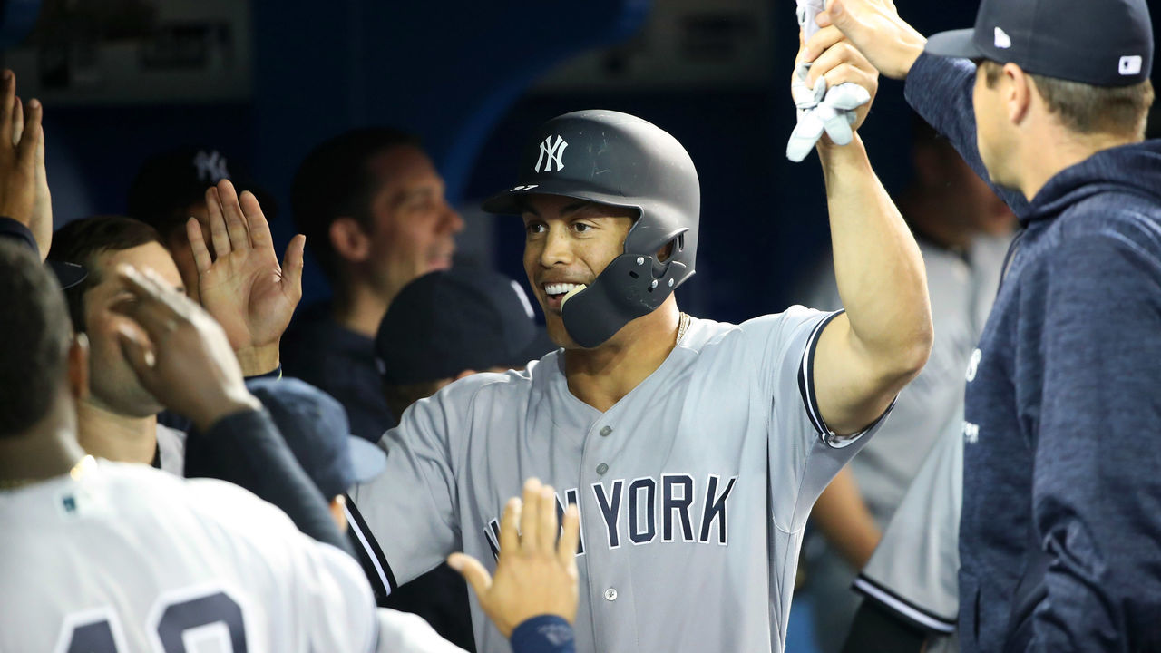 TORONTO, ON - MARCH 29: Giancarlo Stanton #27 of the New York Yankees is congratulated by teammates in the dugout after scoring a run in the fifth inning on Opening Day during MLB game action against the Toronto Blue Jays at Rogers Centre on March 29, 2018 in Toronto, Canada.