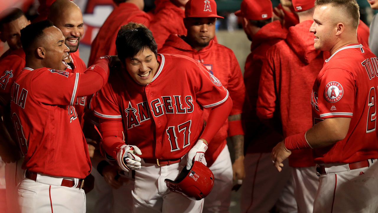 ANAHEIM, CA - APRIL 03: Shohei Ohtani #17 is congratulated by Luis Valbuena #18 and Mike Trout #27 of the Los Angeles Angels of Anaheim in the dugout after hitting a three-run homerun during the first inning of a game against the Cleveland Indians at Angel Stadium on April 3, 2018 in Anaheim, California.