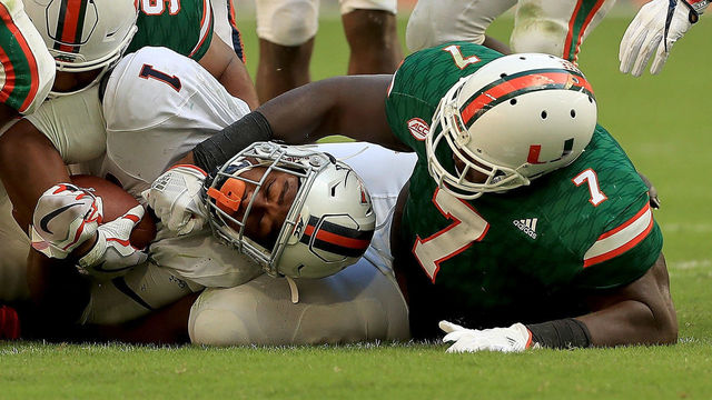 MIAMI GARDENS, FL - NOVEMBER 18: Jordan Ellis #1 of the Virginia Cavaliers is tackled by Kendrick Norton #7 of the Miami Hurricanes during a game at Hard Rock Stadium on November 18, 2017 in Miami Gardens, Florida.