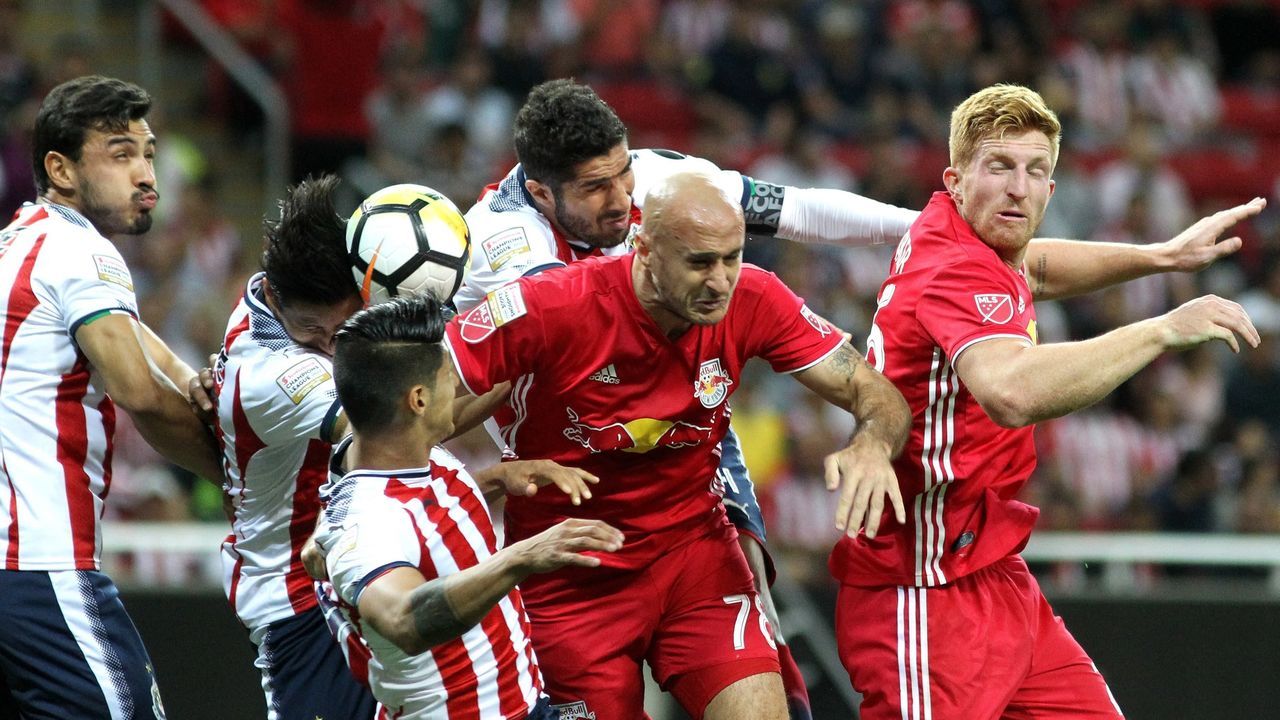 Players of New York Red Bulls (in red) and Mexico´s Guadalajara jump for the ball during the first leg CONCACAF Champions League semifinals match at Akron stadium in Guadalajara, Jalisco State, Mexico on April 4, 2018. / AFP PHOTO / ULISES RUIZ
