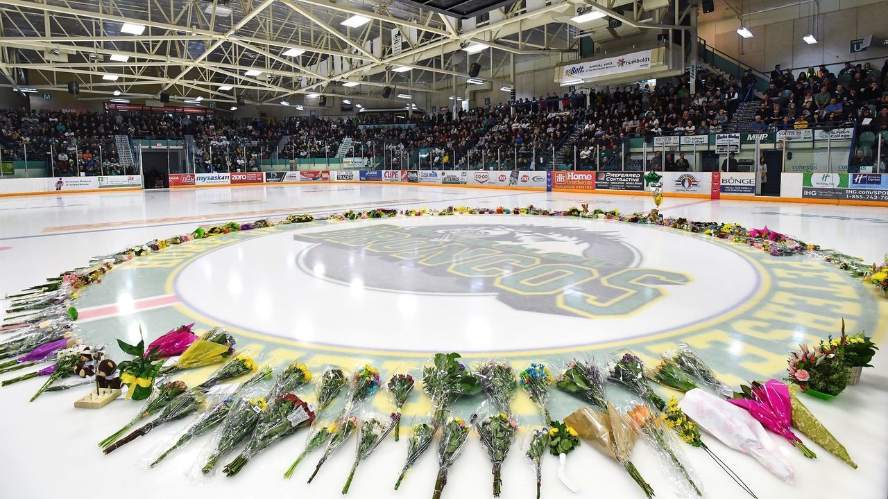 TOPSHOT - Flowers lie at centre ice as people gather for a vigil at the Elgar Petersen Arena, home of the Humboldt Broncos, to honour the victims of a fatal bus accident, April 8, 2018 in Humboldt, Canada. Mourners in the tiny Canadian town of Humboldt, still struggling to make sense of a devastating tragedy, prepared Sunday for a prayer vigil to honor the victims of the truck-bus crash that killed 15 of their own and shook North American ice hockey. / AFP PHOTO / POOL / JONATHAN HAYWARD
