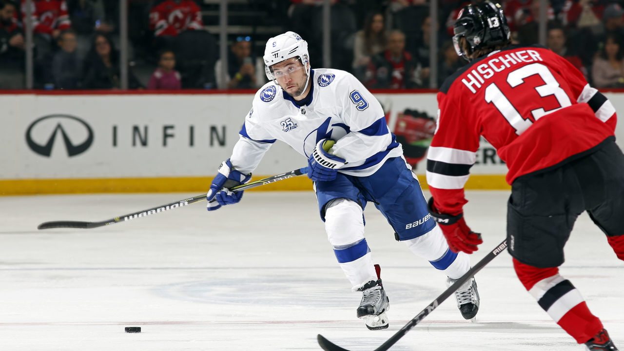 NEWARK, NJ - MARCH 24: Tyler Johnson #9 of the Tampa Bay Lightning passes the puck past Nico Hischier #13 of the New Jersey Devils during the first period at the Prudential Center on March 24, 2018 in Newark, New Jersey.
