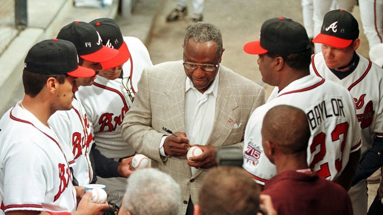 ATLANTA, UNITED STATES: Hank Aaron (C) signs autographs for some of the Atlanta Braves players before ceremonies that unveiled the Hank Aaron Award on the 25th anniversary of his historic 755th home run 08 April 1999. The Hank Aaron Award will be based on the player's combined numbers of hits, home runs and RBI and is scheduled to be presented to the best hitter in each league Championship Series. AFP PHOTO/STEVE SCHAEFER