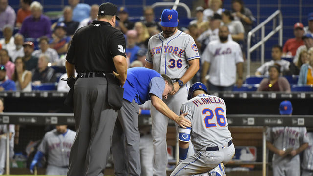 MIAMI, FL - APRIL 11: Manager Mickey Callaway #36 of the New York Mets and Head Athletic Trainer Brian Chicklo talk with Kevin Plawecki #26 after he was hit by a pitch in the eighth inning against the Miami Marlins at Marlins Park on April 11, 2018 in Miami, Florida.