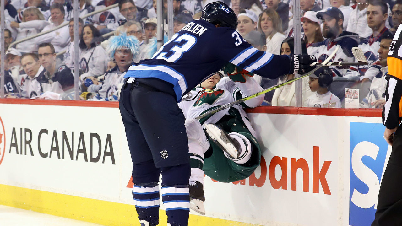 WINNIPEG, MB - APRIL 13: Dustin Byfuglien #33 of the Winnipeg Jets crunches Mikko Koivu #9 of the Minnesota Wild into the end boards during second period action in Game Two of the Western Conference First Round during the 2018 NHL Stanley Cup Playoffs at the Bell MTS Place on April 13, 2018 in Winnipeg, Manitoba, Canada.