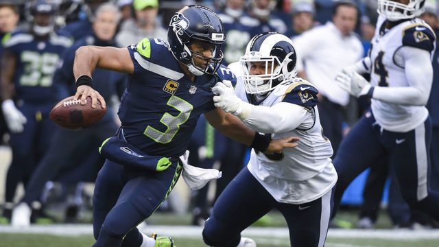 SEATTLE, WA - DECEMBER 17: Quarterback Russell Wilson #3 of the Seattle Seahawks tries to keep defensive tackle Aaron Donald #99 of the Los Angeles Rams at bay in the 2nd quarter of the game at CenturyLink Field on December 17, 2017 in Seattle, Washington.