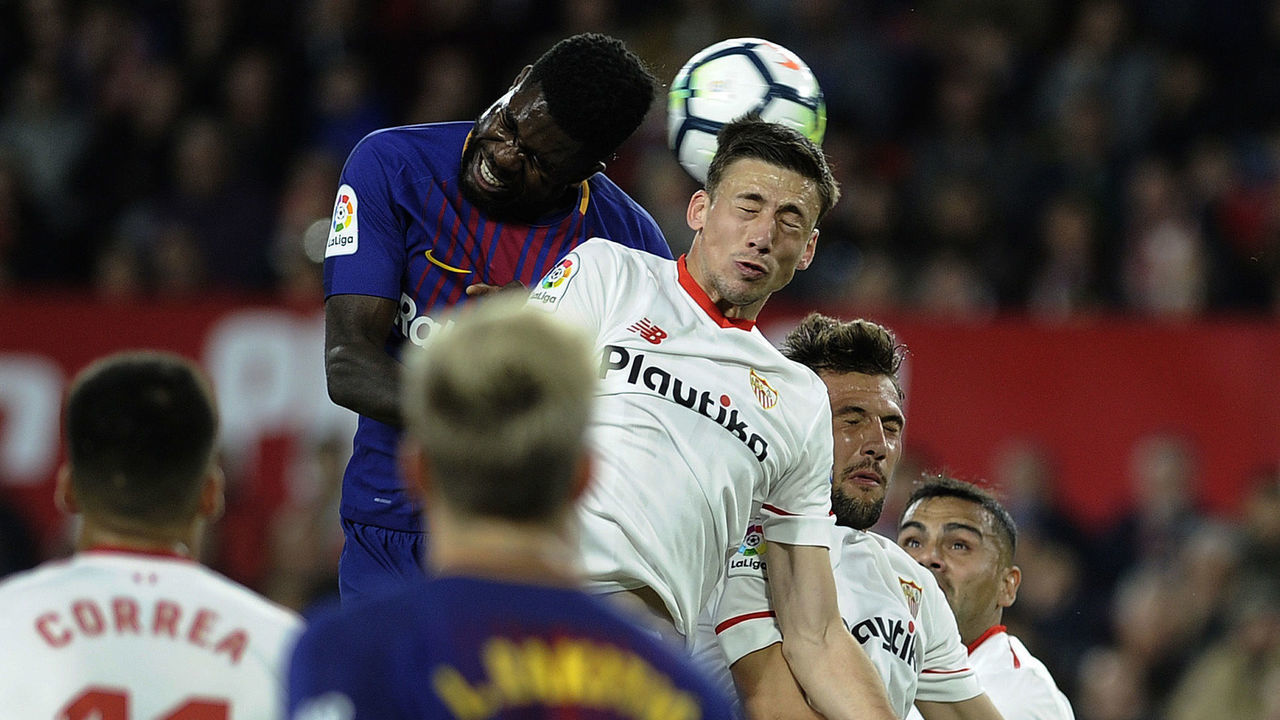 Barcelona's French defender Samuel Umtiti (L) jumps for the ball with Sevilla's French defender Clement Lenglet during the Spanish League football match between Sevilla FC and FC Barcelona at the Ramon Sanchez Pizjuan stadium on March 31, 2018. / AFP PHOTO / Cristina Quicler