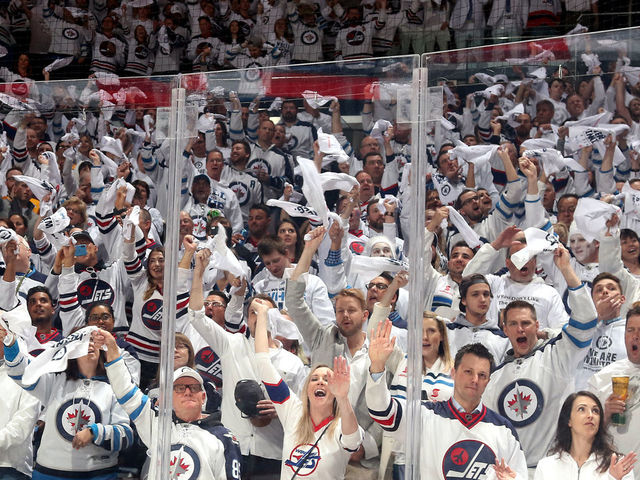 WINNIPEG, MB - MAY 1: Winnipeg Jets fans clad in all white rise to their feet and cheer prior to puck drop between the Jets and the Nashville Predators in Game Three of the Western Conference Second Round during the 2018 NHL Stanley Cup Playoffs at the Bell MTS Place on May 1, 2018 in Winnipeg, Manitoba, Canada.