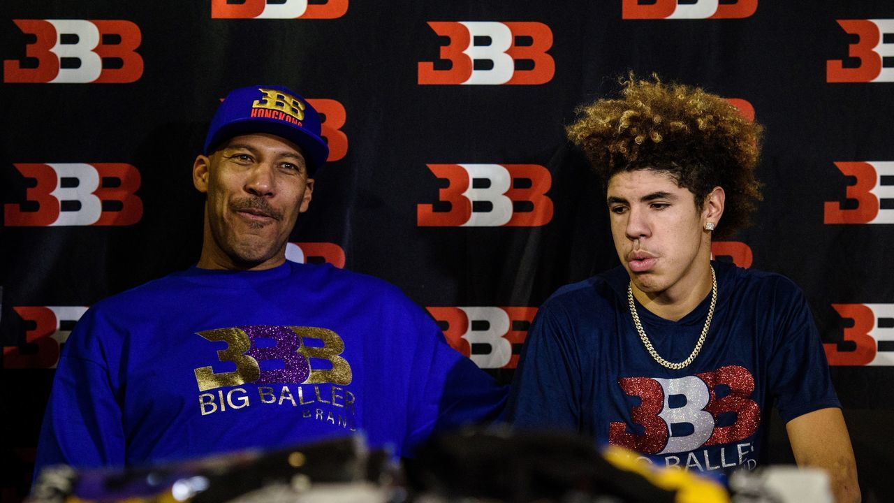 LaVar Ball (L), father of basketball player LiAngelo Ball and the owner of the Big Baller brand, sits with his other son LaMelo Ball during a promotional event in Hong Kong on November 14, 2017. UCLA players LiAngelo Ball -- the younger brother of Los Angeles Lakers rookie star Lonzo Ball -- and teammates Cody Riley and Jalen Hill were arrested on November 7 in Hangzhou ahead of their regular-season-opening game against Georgia Tech in nearby Shanghai this past weekend. ESPN reported that they were nabbed on suspicion of stealing from a Louis Vuitton store and later freed on bail but ordered to remain in Hangzhou. / AFP PHOTO / Anthony WALLACE