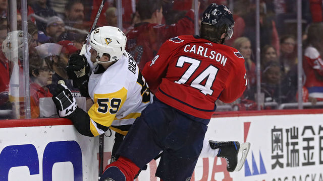 WASHINGTON, DC - MAY 05: John Carlson #74 of the Washington Capitals is checked by Jake Guentzel #59 of the Pittsburgh Penguins during the third period in Game Five of the Eastern Conference Second Round during the 2018 NHL Stanley Cup Playoffs at Capital One Arena on May 5, 2018 in Washington, DC.