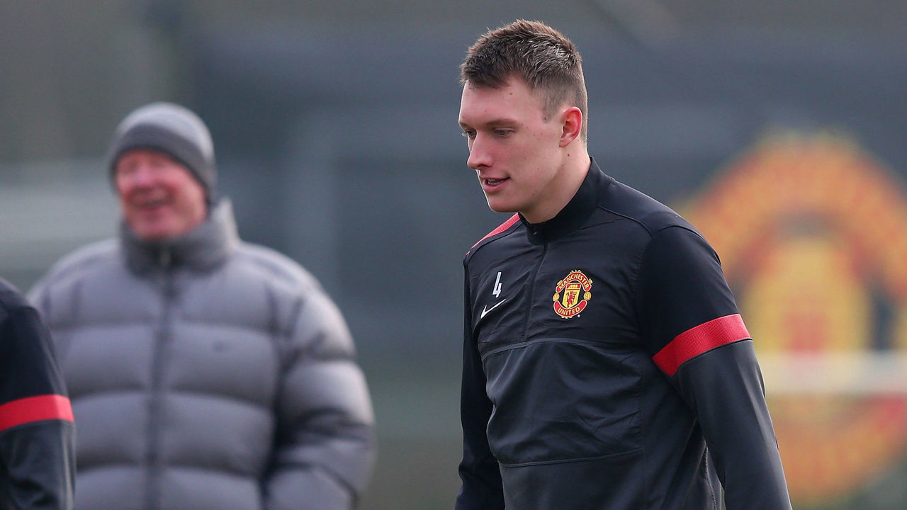 MANCHESTER, ENGLAND - FEBRUARY 12: Phil Jones of Manchester United passes the ball as Sir Alex Ferguson looks on in the background during a training session at the Carrington Training Ground on February 12, 2013 in Manchester, England.